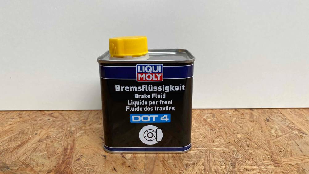 Bremsflüssigkeit getestet: Ein Kanister auf einer Holzoberfläche vor heller Wand von Vorne