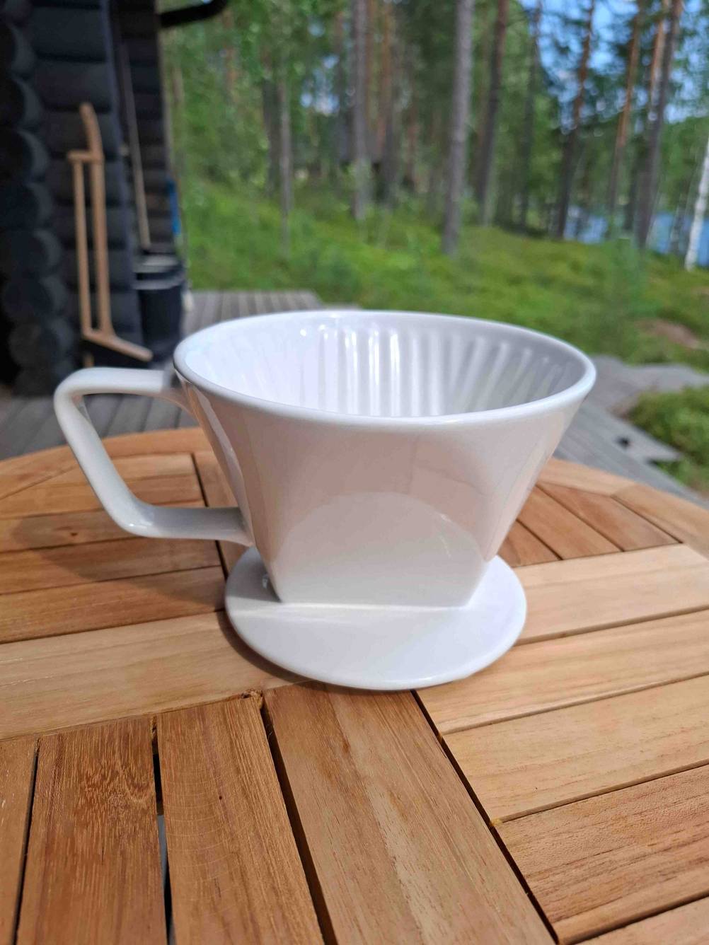 Ein getesteter Porzellan-Kaffeefilter in der Farbe Weiß steht auf einem Tisch im Außenbereich.