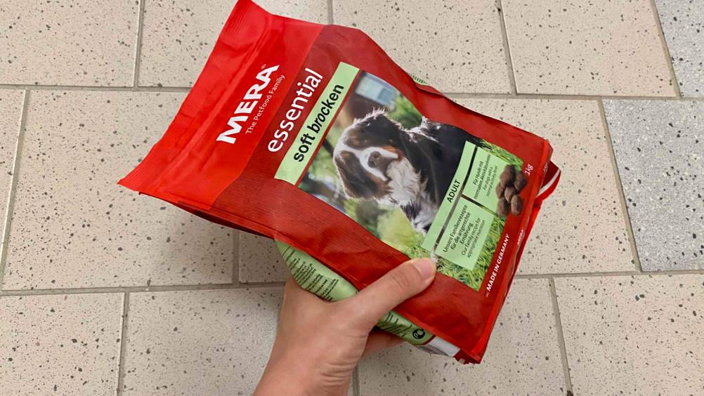 Mera-Hundefutter im Test: Eine Hand hält eine Packung Mera-Hundefutter vor einen hellen Hintergrund