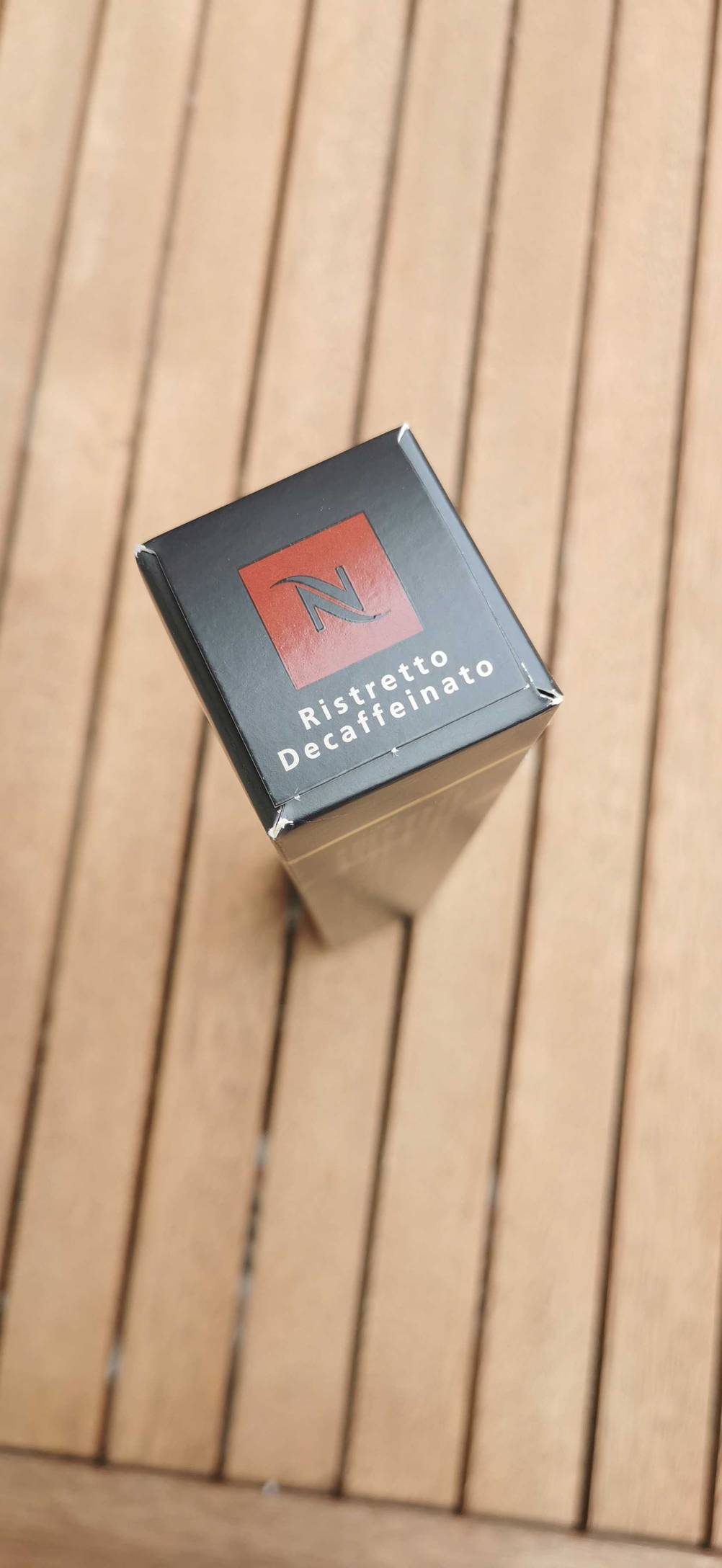 Auf einem Holzuntergrund steht eine Packung des getesteten entkoffeinierten Kaffees hochkant.
