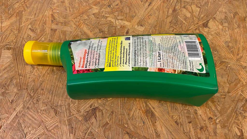 Rosendünger im Test: Eine Flasche liegt mit ihrer Rückseite nach oben auf einer Holzfläche