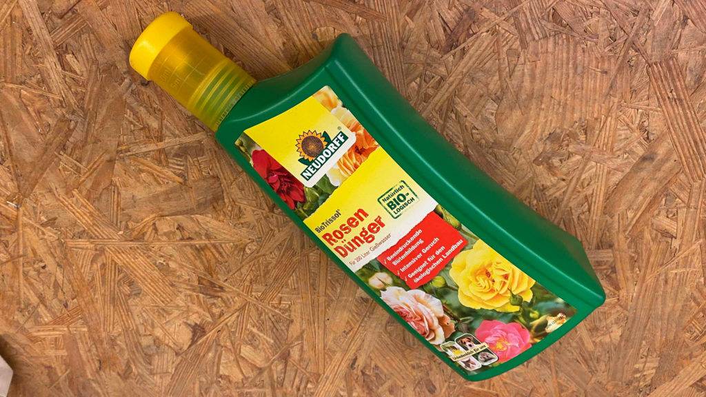 Rosendünger im Test: Eine Flasche liegt quer auf einer Holzfläche