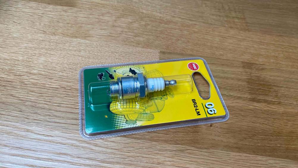 Zündkerze getestet: Eine verpackte Zündkerze liegt quer auf einer Holzfläche.