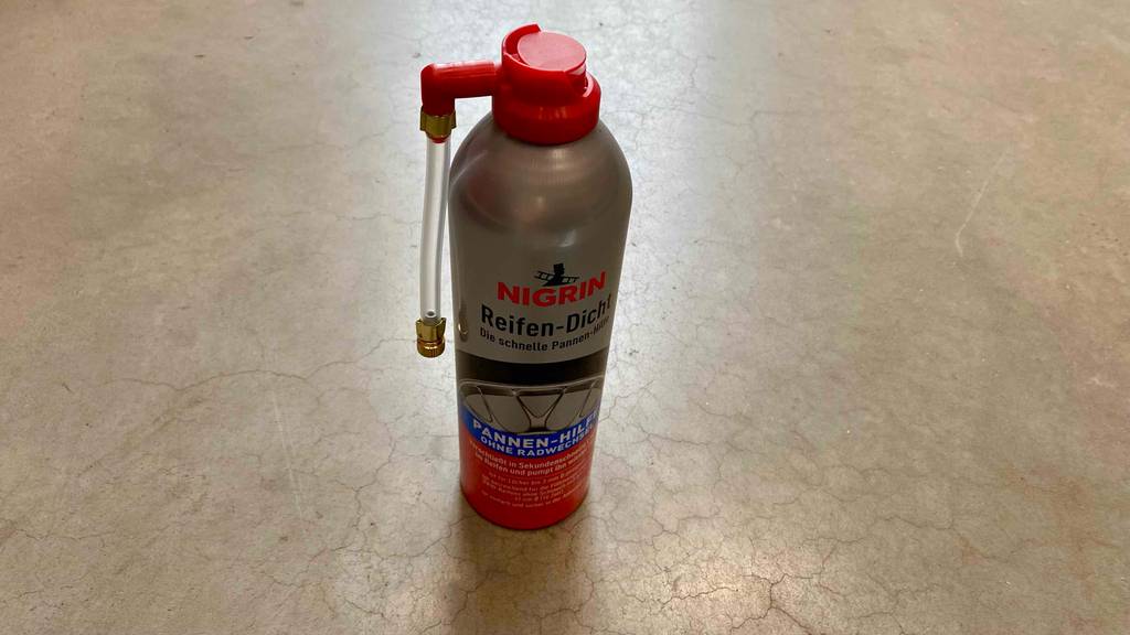 Reifendichtmittel getestet: eine Flasche Reifendichtmittel der Marke Nigrin stehend auf einem Boden.