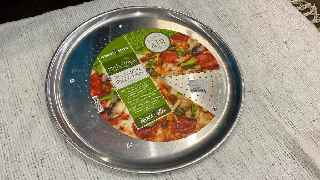 Ein getestetes Pizzablech mit 16 cm Durchmesser auf einem weißen Stoff platziert.
