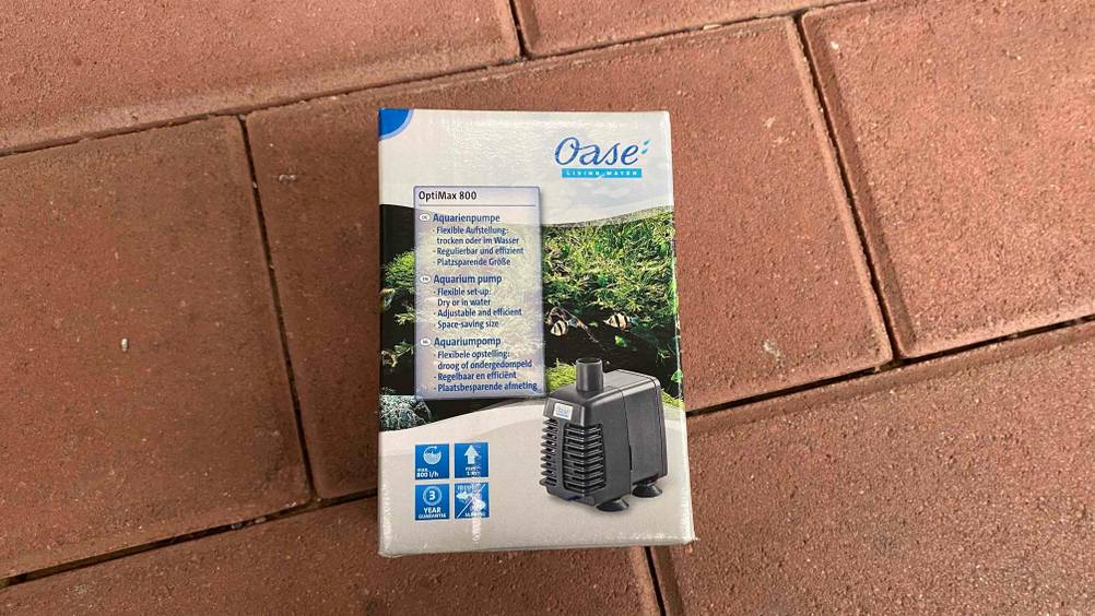 Aquarium-Pumpe getestet: Eine verpackte Pumpe liegt auf einem Steinboden.