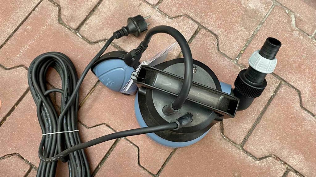 Tauchpumpe im Test: Tauchpumpe der Marke Obi steht auf steiniger Oberfläche