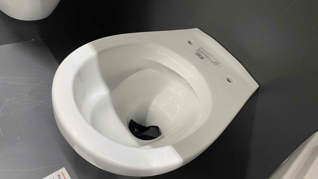 Spülrandloses-WC getestet: Ein Spülrandloses-WC ohne Deckel an einer Wand befestigt.