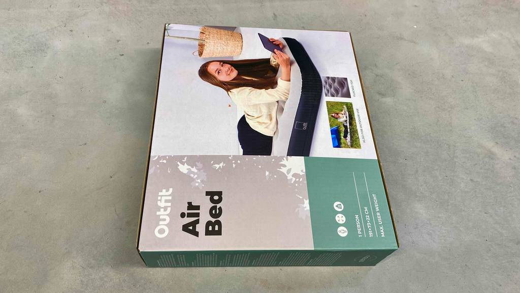 Luftbett getestet: Ein verpacktes Bett liegt vertikal auf einer grauen Fläche.