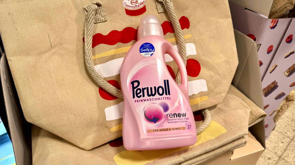 Das Perwoll-Renew Feinwaschmittel lehnt an einer Tasche.