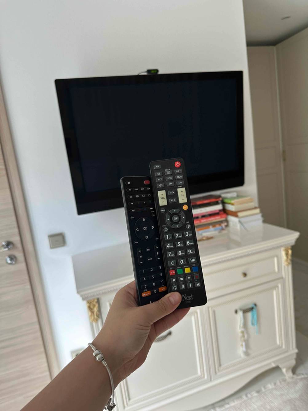 49-Zoll-Fernseher im Test: zwei Fernbedienungen werden vor dem Fernseher gehalten.