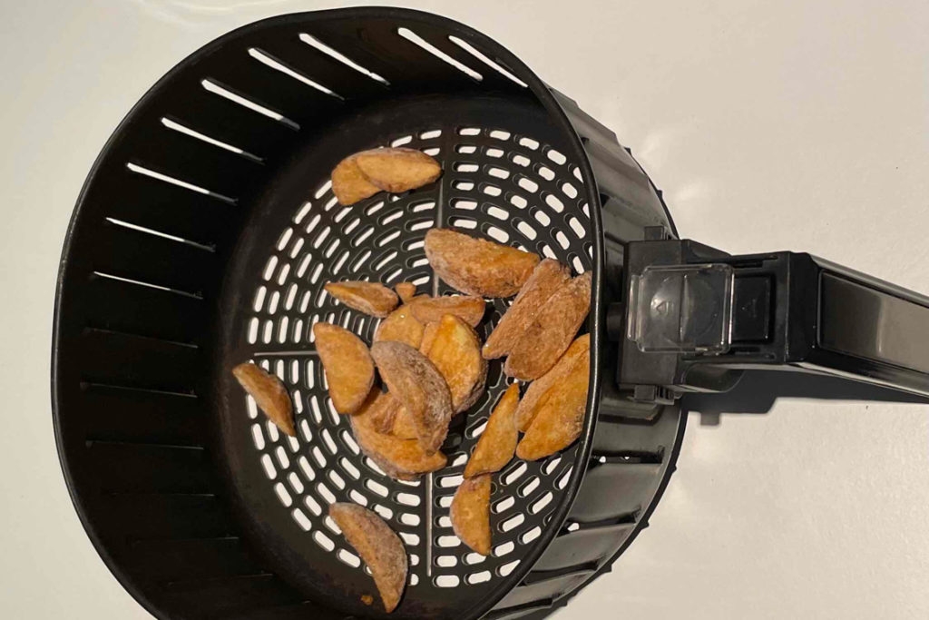 Heißluftfritteuse XXL getestet: Ein Siebeinsatz mit Kartoffeln auf heller Oberfläche