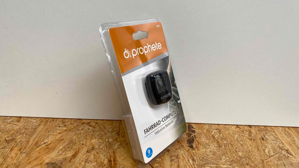 Fahrradcomputer im Test: Ein origialverpacktes Gerät steht auf einer Holzfläche vor einer weißen Wand