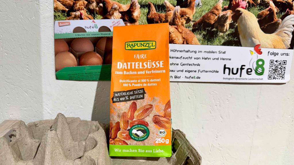 Der getestete Dattelzucker in einer orangefarbenen 250-g-Verpackung steht auf einem Eierkarton.
