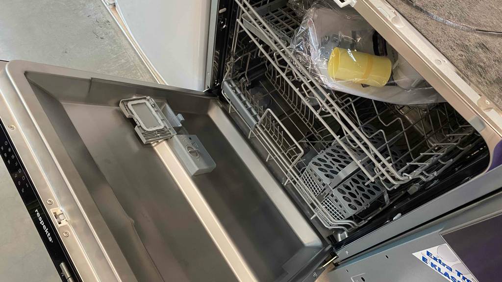 Einbau-Geschirrspüler getestet: Nahaufnahme von einem geöffneten Einbau-Geschirrspüler inklusive Zubehör und Beschreibung, der in einem Verkaufsbereich steht.