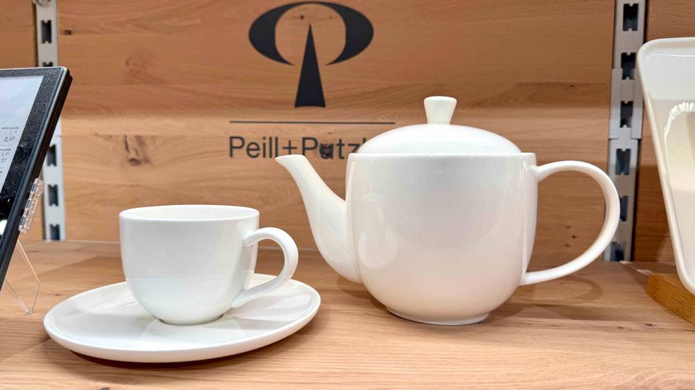 Teeservice-Test: Eine weiße Teekanne steht neben einer Teetasse mit Untersetzer.