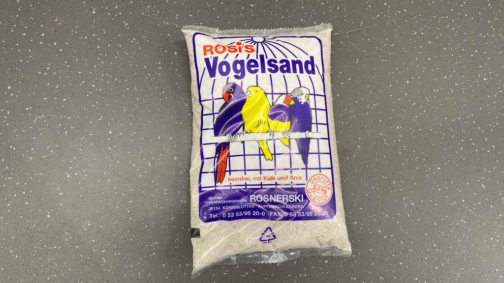 Vogelsand getestet: eine durchsichtige Packung Vogelsand liegt auf einem Boden mit 2,5 kg Inhalt.