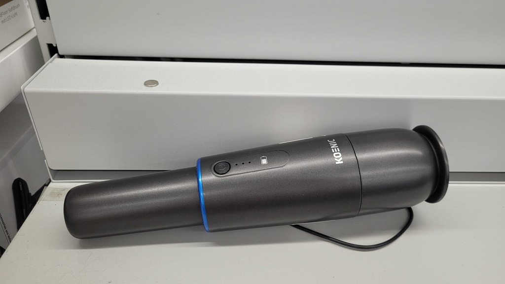 Ein schwarzer getesteter Autostaubsauger von Koenic im liegenden Zustand.