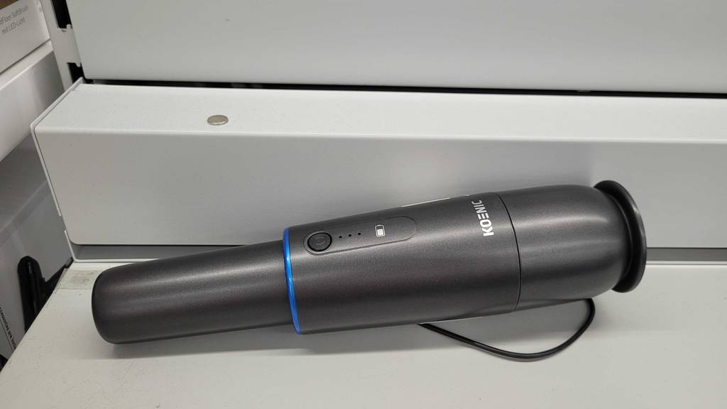 Ein schwarzer getesteter Autostaubsauger von Koenic im liegenden Zustand.