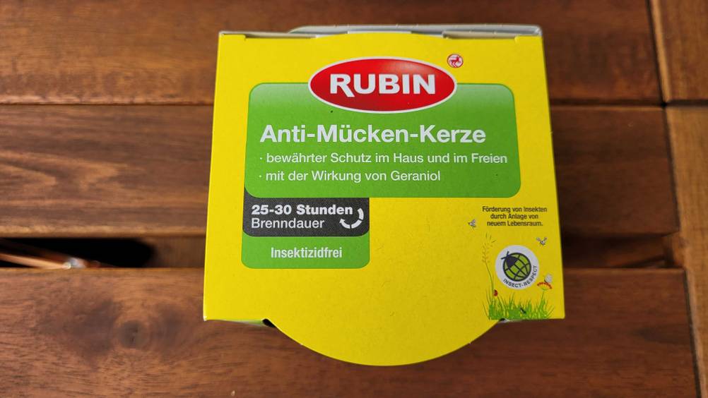 Eine verpackte Anti-Mücken-Kerze von oben auf einer Holzoberfläche.