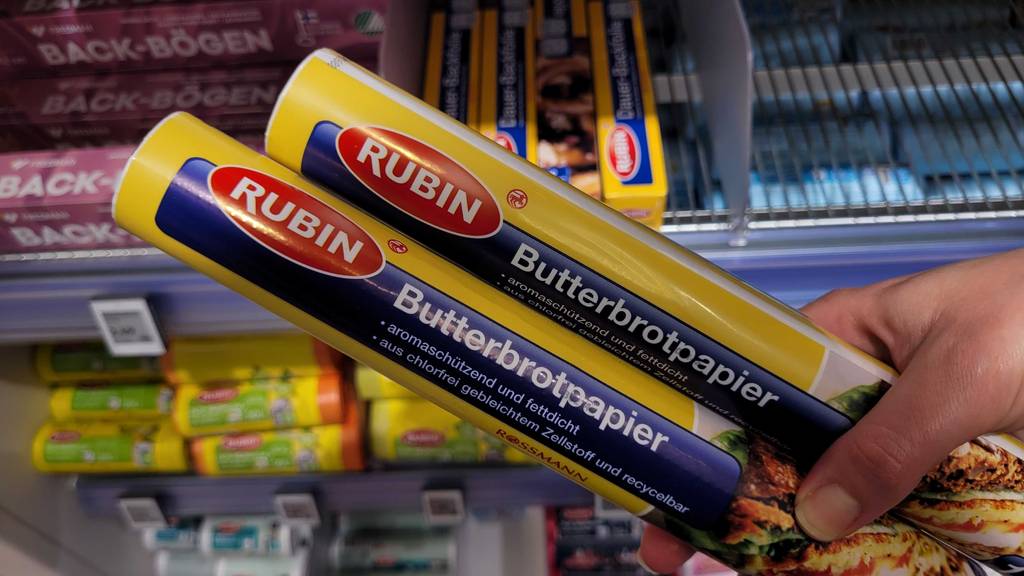 Zwei Packungen des getesteten Butterbrotpapiers werden in der Hand gehalten.