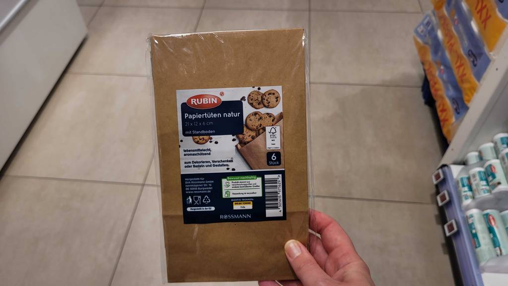 Test: Braune Papiertüten werden mit der Vorderseite ersichtlich in der Hand gehalten.