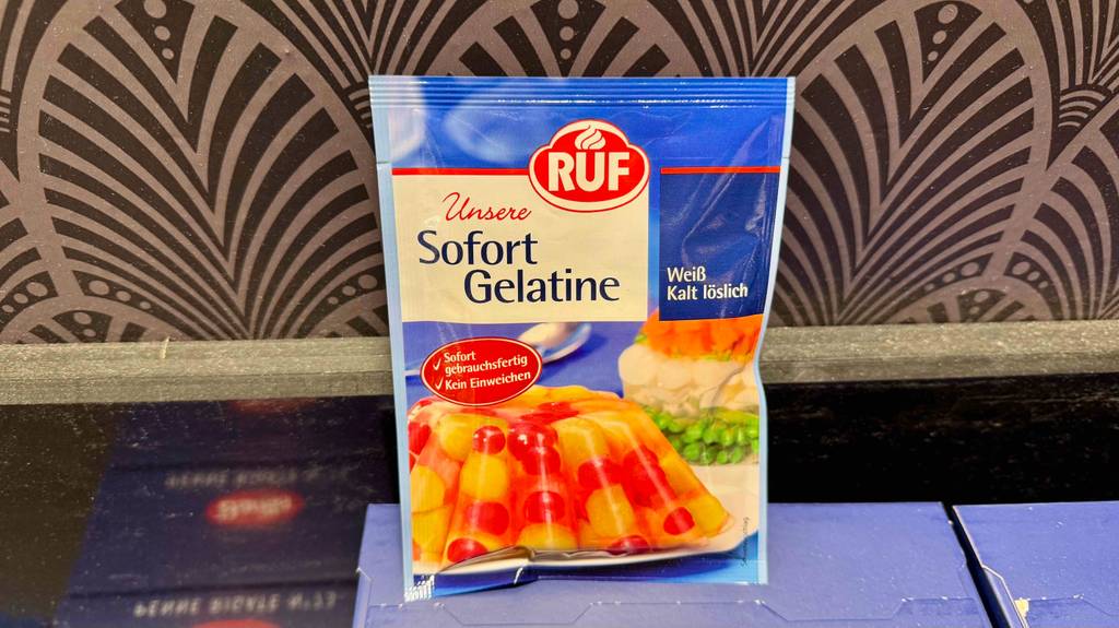 Eine Packung getestetes Gelatine-Pulver steht auf einer blauen Verpackung.
