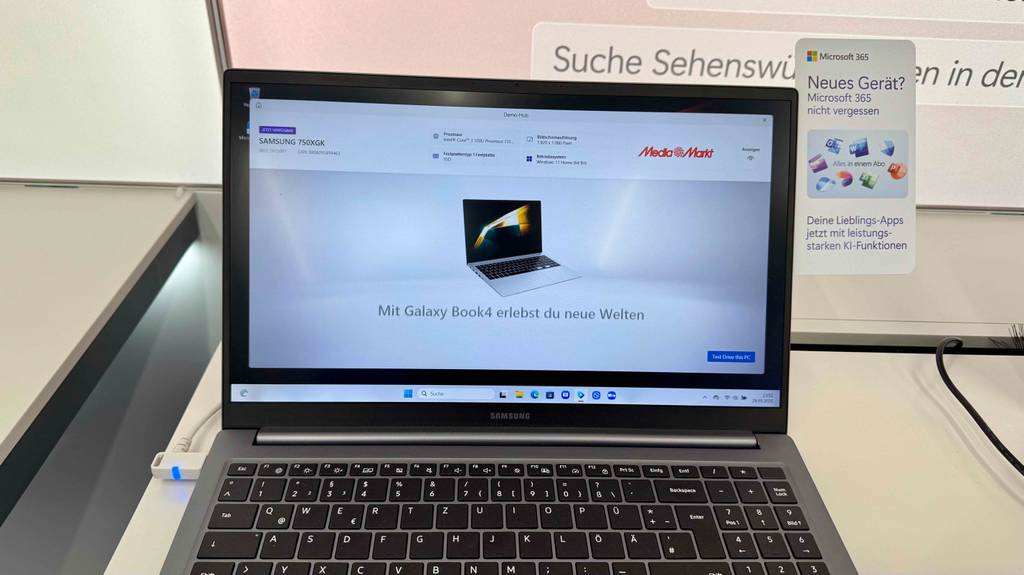 Ansicht von vorn auf das getestete Laptop bis 800 Euro, das eingeschaltet auf einem Ausstellungstisch im Geschäft steht.
