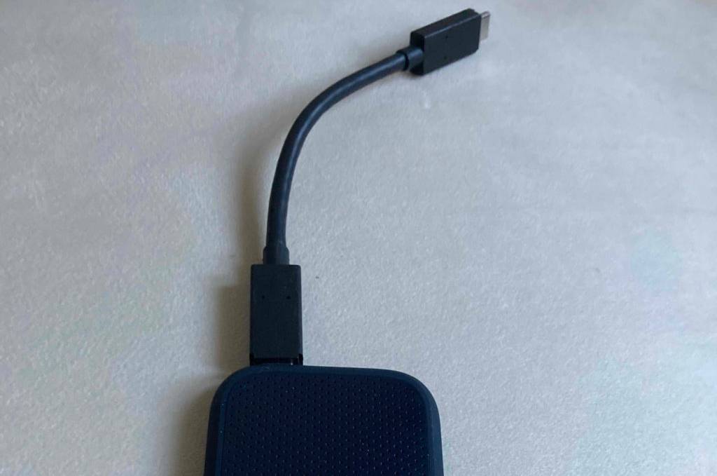 Eine getestete SSD (2TB) mit Kabel auf einer hellen Oberfläche liegend.