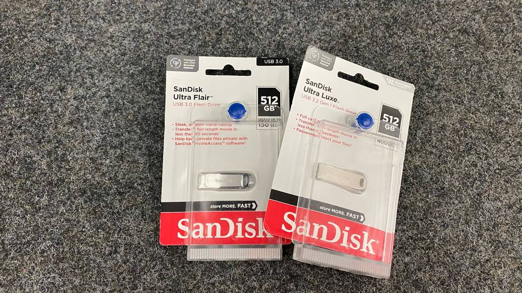 Zwei getestete USB-Stick (512GB) in Verpackung leicht übereinander liegend auf einer dunklen Fläche.