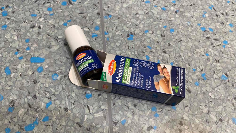 Eine Flasche getestetes Melatonin-Spray schaut aus seiner Origianlverpackung hervor