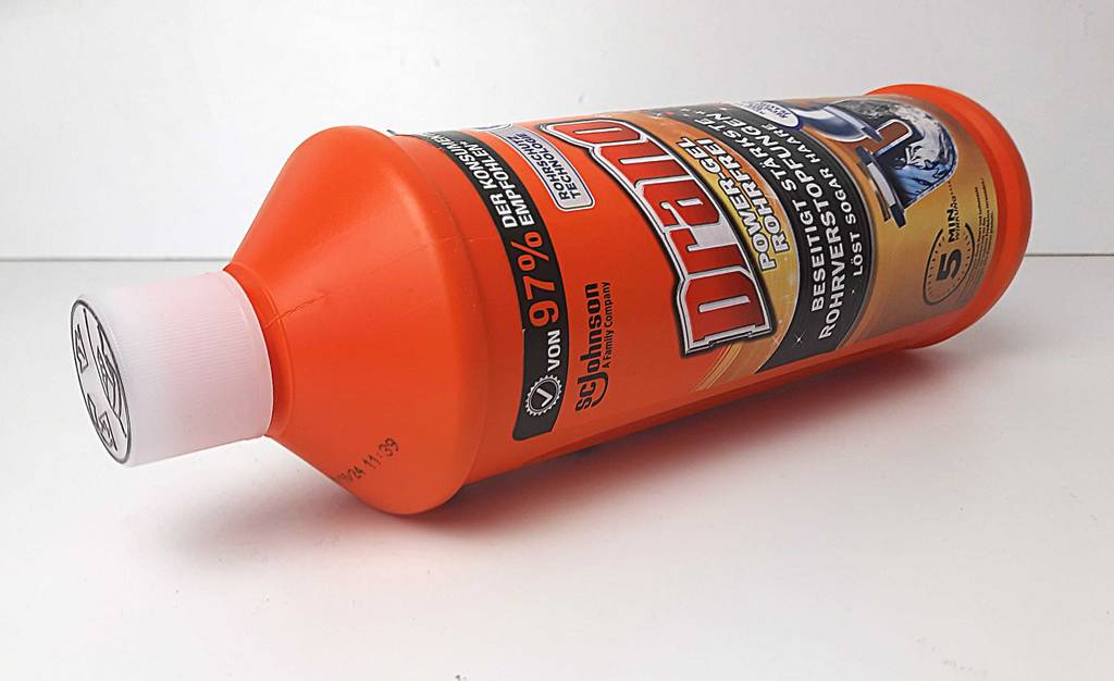 Die getestete Rohrreinigung liegt in der orangefarbenen Kunststoffflasche auf einer weißen Fläche.