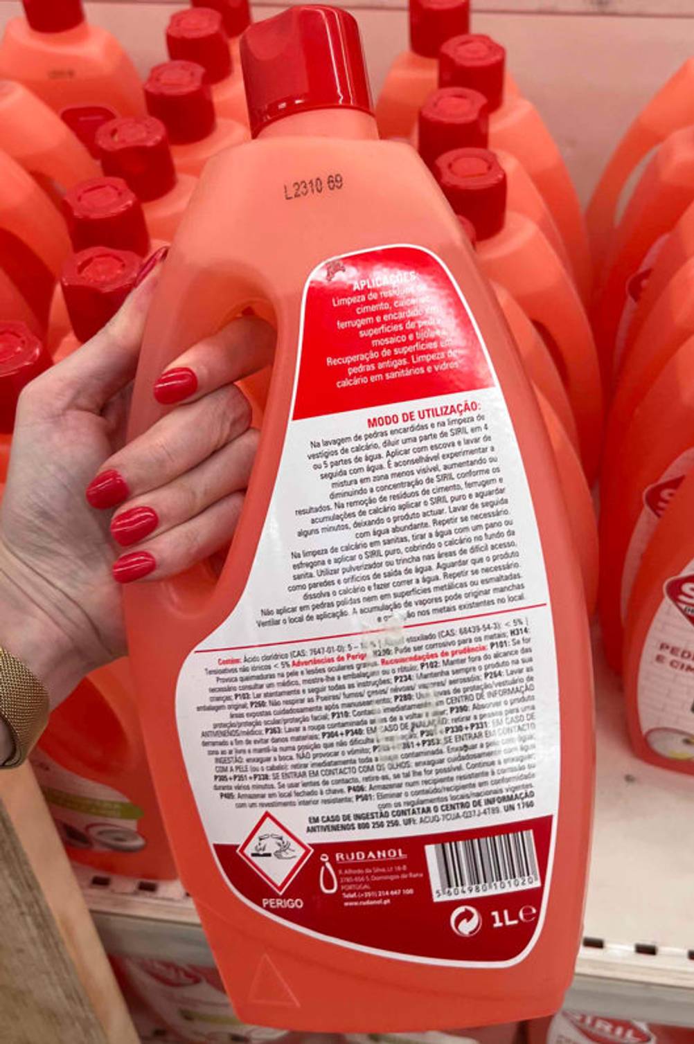 Entkalker-Test: Orangefarbige Entkalker-Flasche wird in der Hand gehalten - Rückseite ersichtlich.