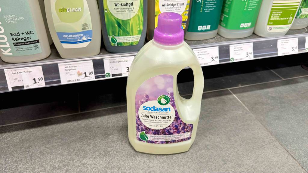 Das getestete Colorwaschmittel steht vor einem Regal worin sich andere Waschmittel befinden.