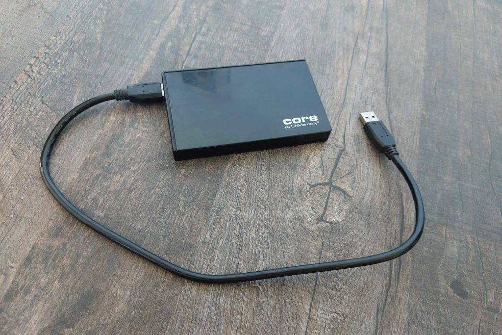 SSD Festplatte im Test: Eine Festplatte und ihr Kabel auf einer Holzoberfläche