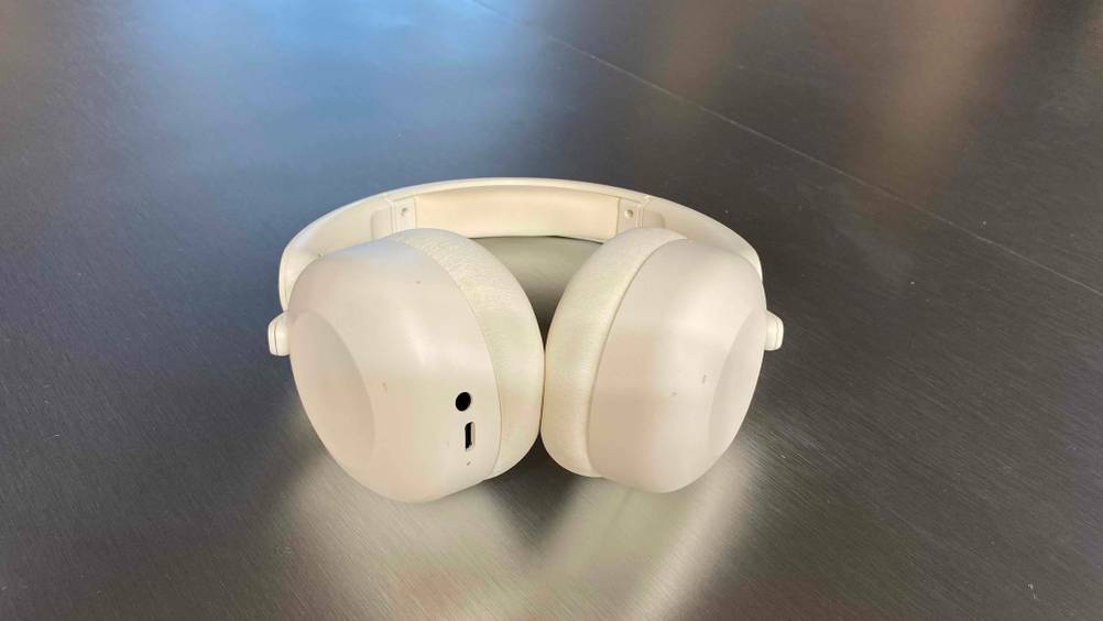 Ein getesteter Over-Ear-Kopfhörer von schräg unten auf einer glänzenden Fläche mit Sicht auf die Anschlüsse.
