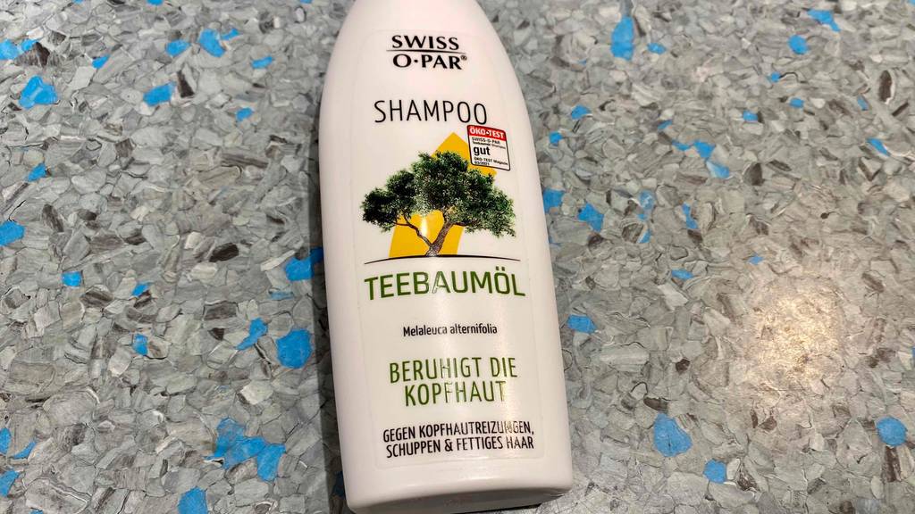 Getestetes Teebaum-Shampoo liegend auf einem Boden, mit Hinweis zur Wirkung.