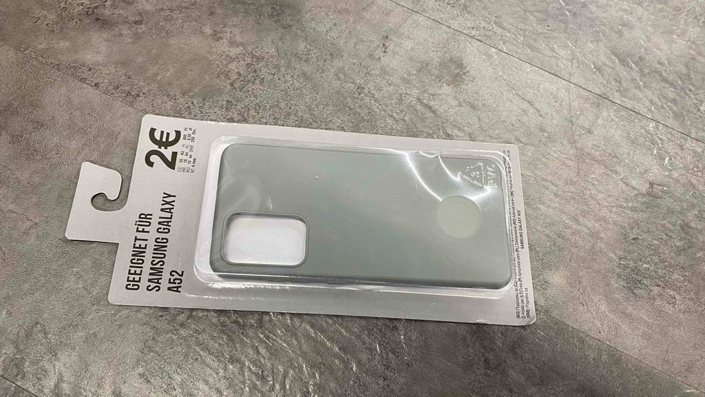 Samsung-Galaxy-A52-Hülle getestet: Ein verpacktes Proukt liegt quer auf einem grauen Boden.