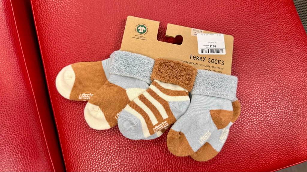 Getestete Babysocken in der Größe 15 - 18 liegen auf einem roten Hocker.