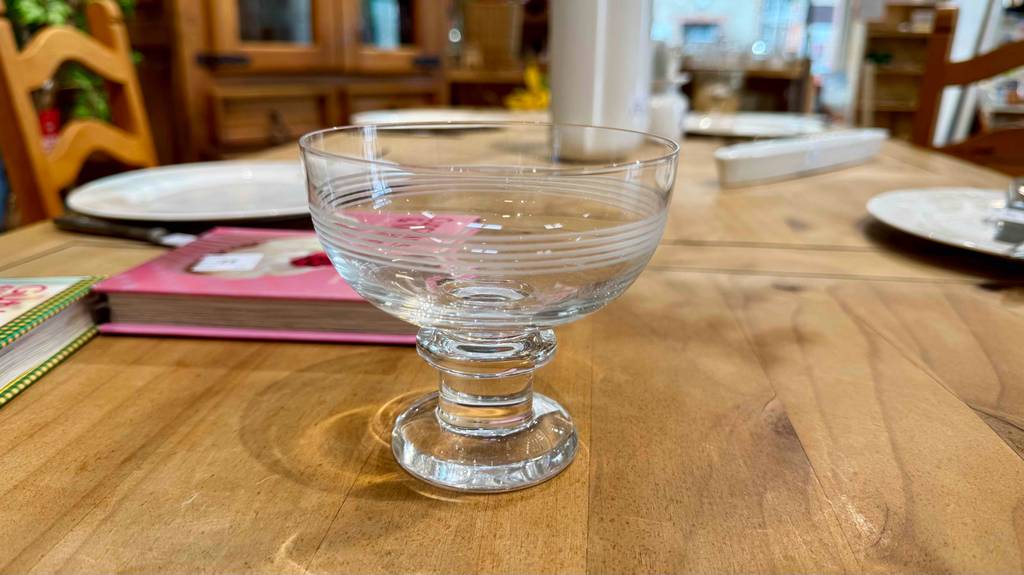Auf einem Holztisch steht der getestete Eisbecher aus Glas vor Büchern und Tellern.