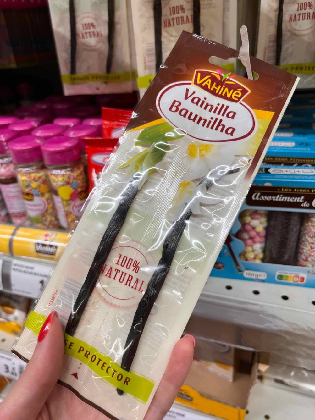 Vanilleschoten im Test: Eine Hand hält eine Packung mit Schoten hoch im Hintergrund ein Regal