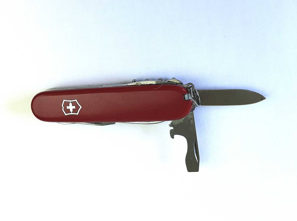 Das getestete Victorinox-Taschenmesser liegt auf einer weißen Fläche, während der Flaschenöffner und das Messer ausgeklappt sind.
