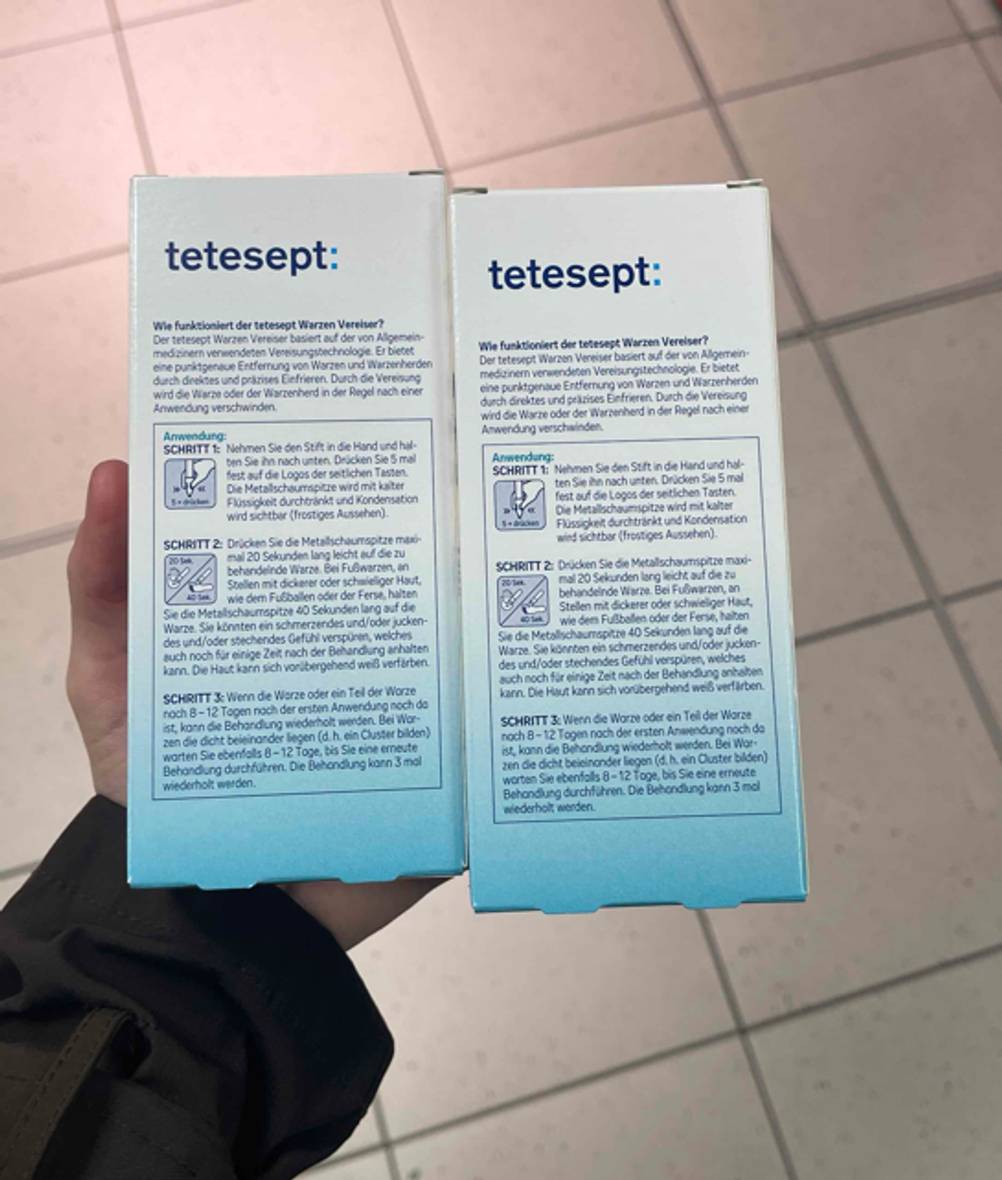 Warzenvereiser-Test: zwei identische Verpackungen des Warzenvereisers werden nebeneinander in der Hand gehalten.