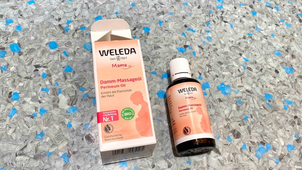 Ein getestetes Damm-Masageöl von Weleda liegt neben der entsprechenden Verpackung.