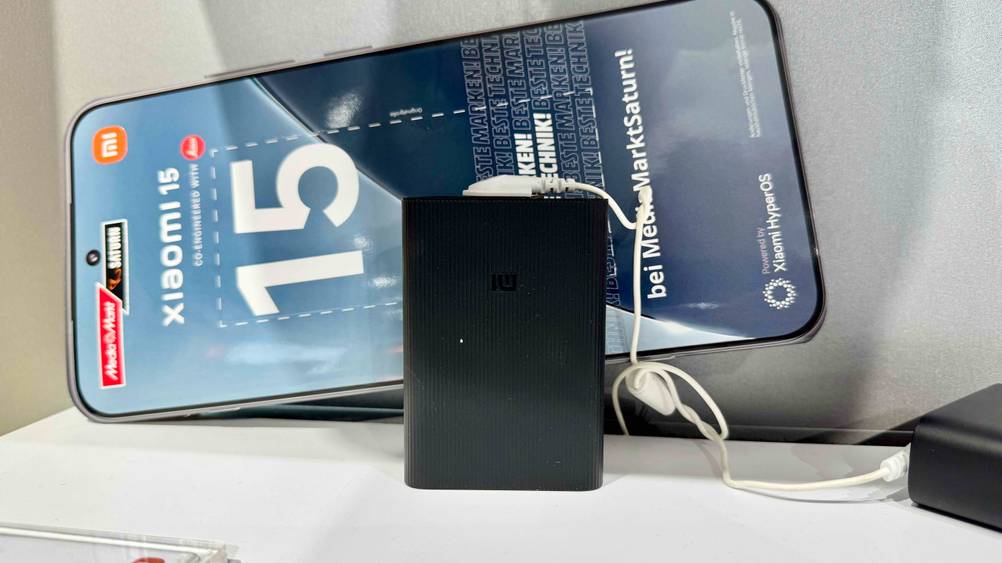 Die getestete Xiaomi-Powerbank steht vertikal auf einem weißen Tisch und ist an einem weißen Kabel angesteckt.