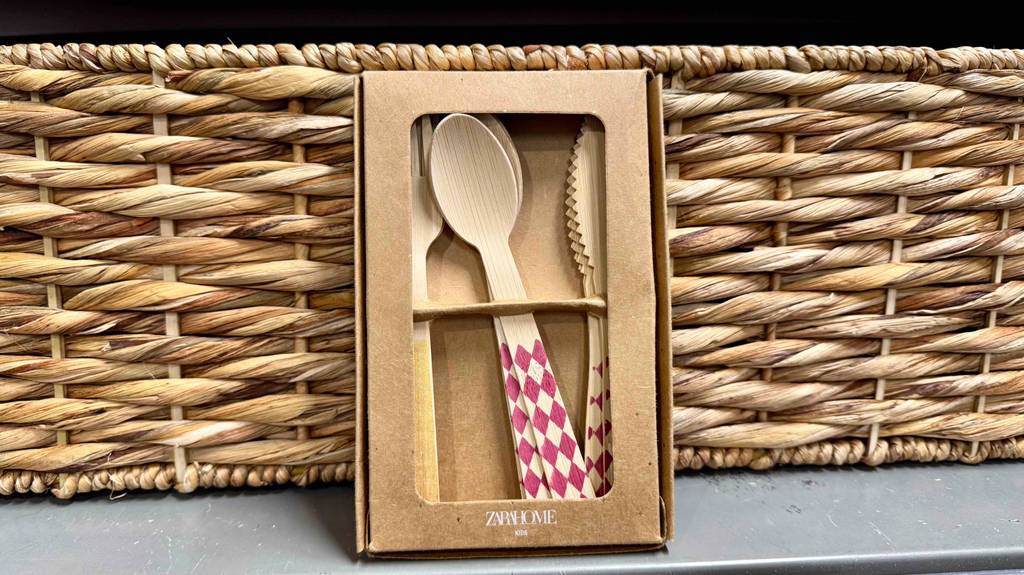 Test: Ein Holzbesteck mit bunten Griffen steht vor einem Korb.