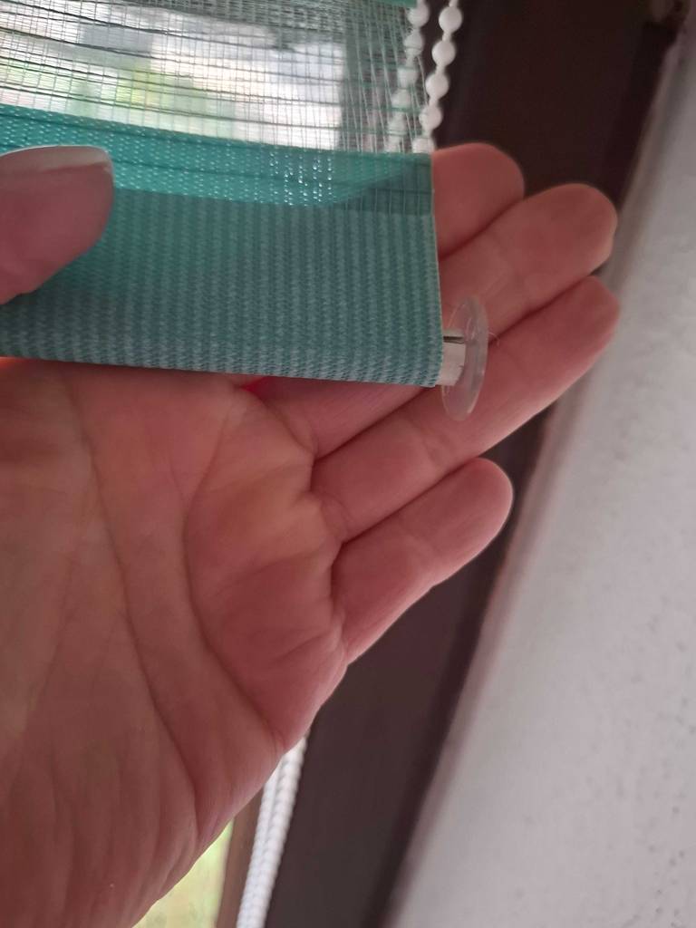 Eine Hand hält das Verdunkelungsrollo im Test am unteren Ende.