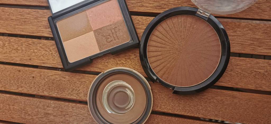 Bronzer im Test: 3 geöffnete Bronzer liegen auf einem Holztisch.
