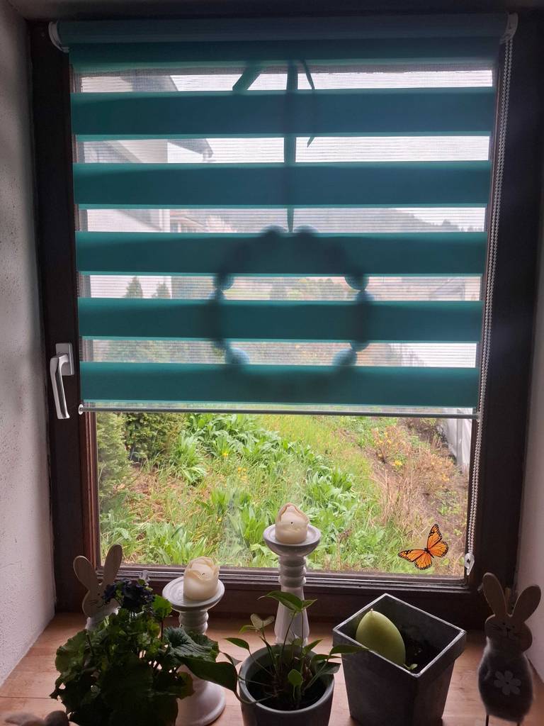 Das getestete Verdunkelungsrollo mit grünen Streifen hängt an einem Fenster.