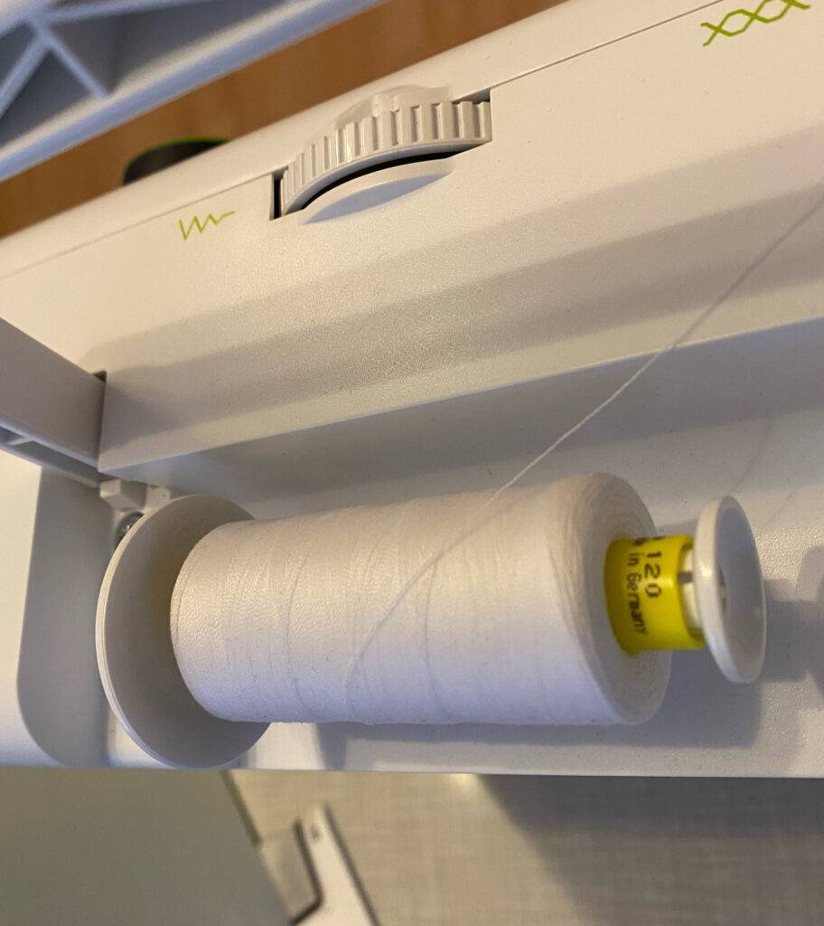 Nähmaschine im Test: ein weißer Faden ist auf der Halterung einer Nähmaschine befestigt.